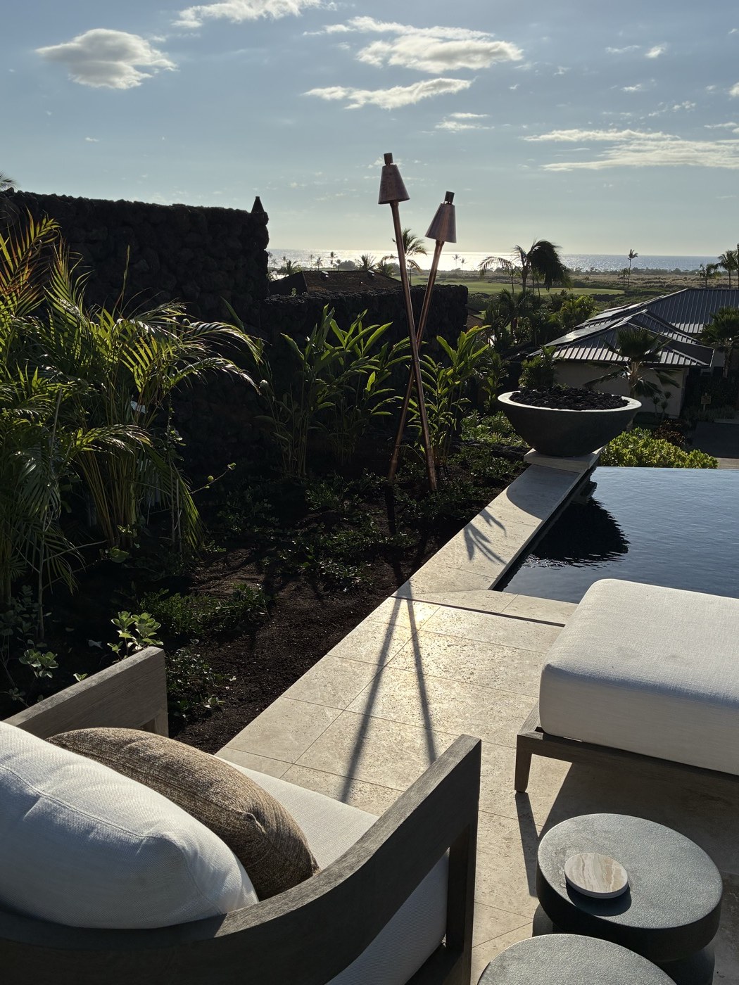 Crossed copper tikis on a luxury Kona estate terrace with ocean view