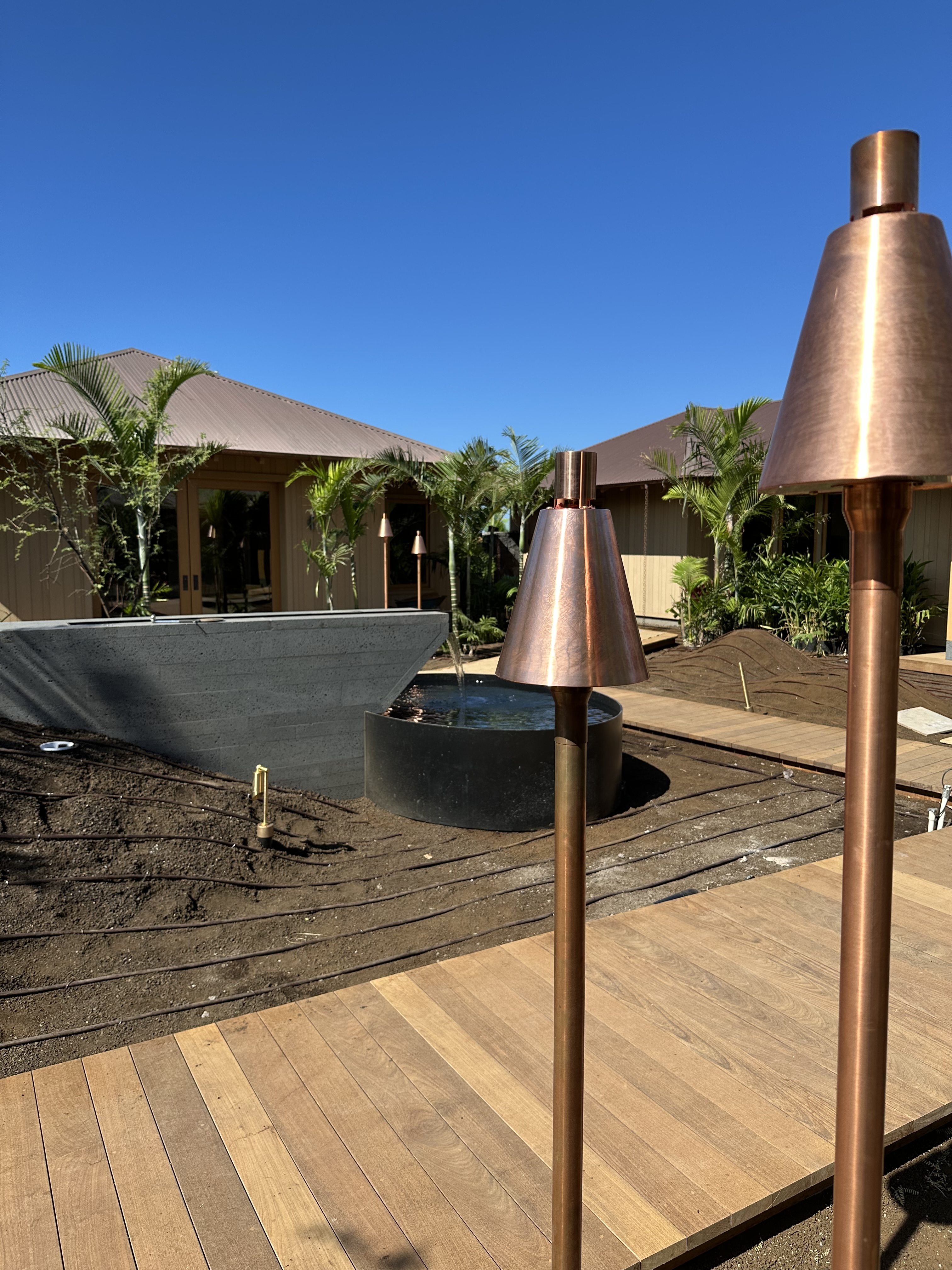 Crossed tiki torches installed in lava rock with palm trees and Pacific horizon